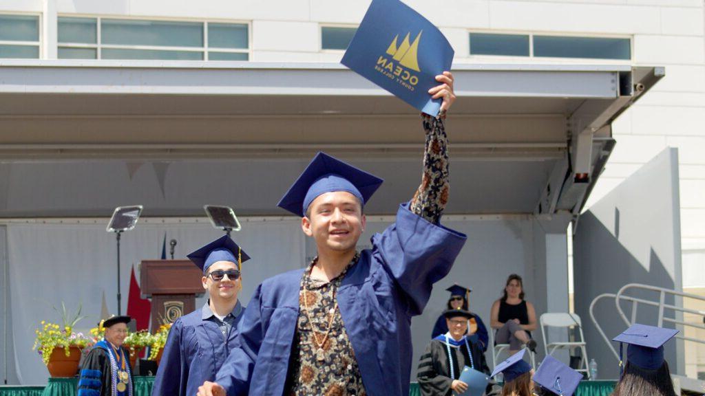 student holding up diploma at graduation 